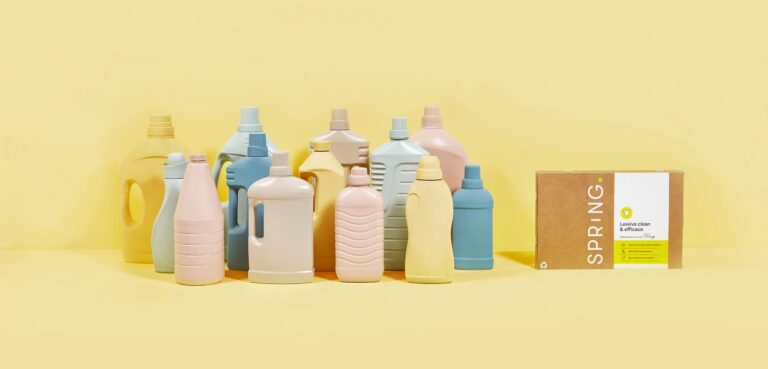 Bouteille d'adoucissant posée à côté d'une pile de linge propre, illustrant son usage pour assouplir les vêtements.