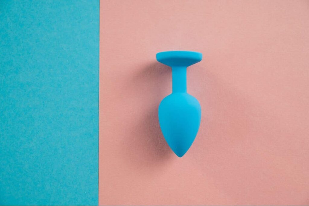 Un plug anal en silicone noir posé sur une surface réfléchissante