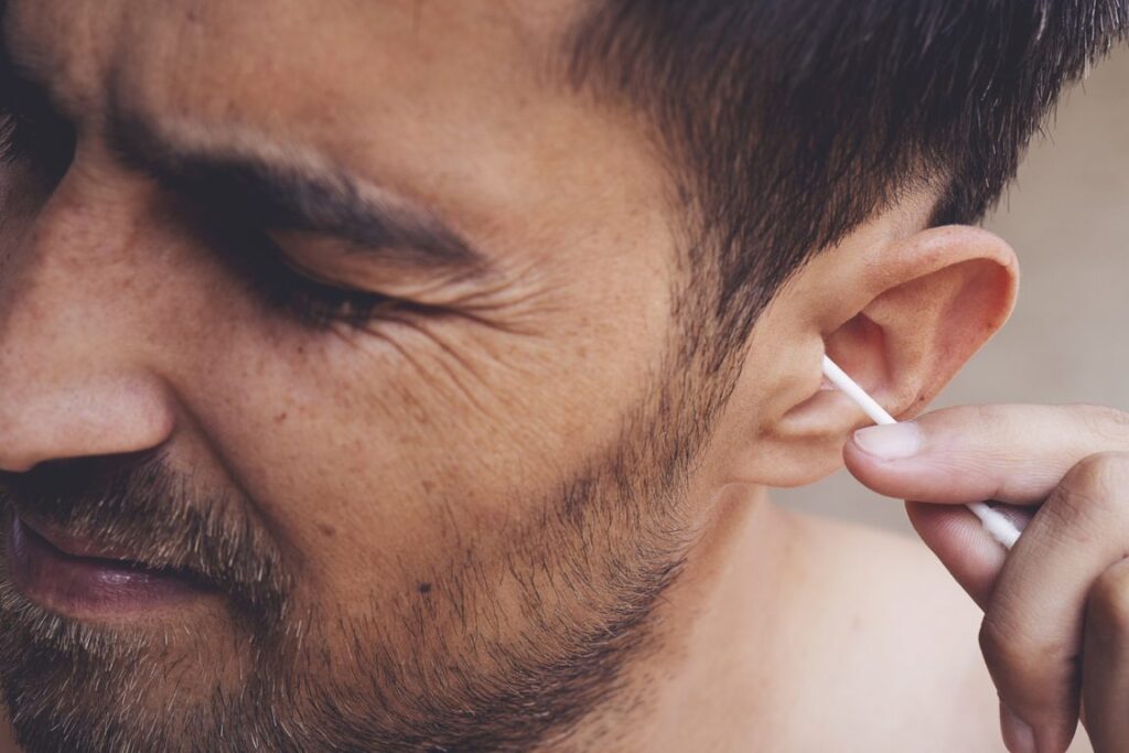 Gros plan sur une oreille nettoyée avec un coton-tige, illustrant les risques pour le cérumen.