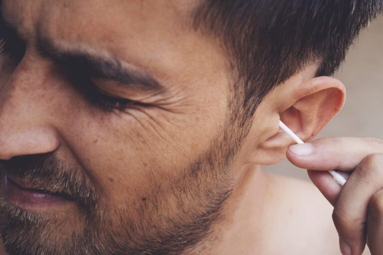 Gros plan sur une oreille nettoyée avec un coton-tige, illustrant les risques pour le cérumen.